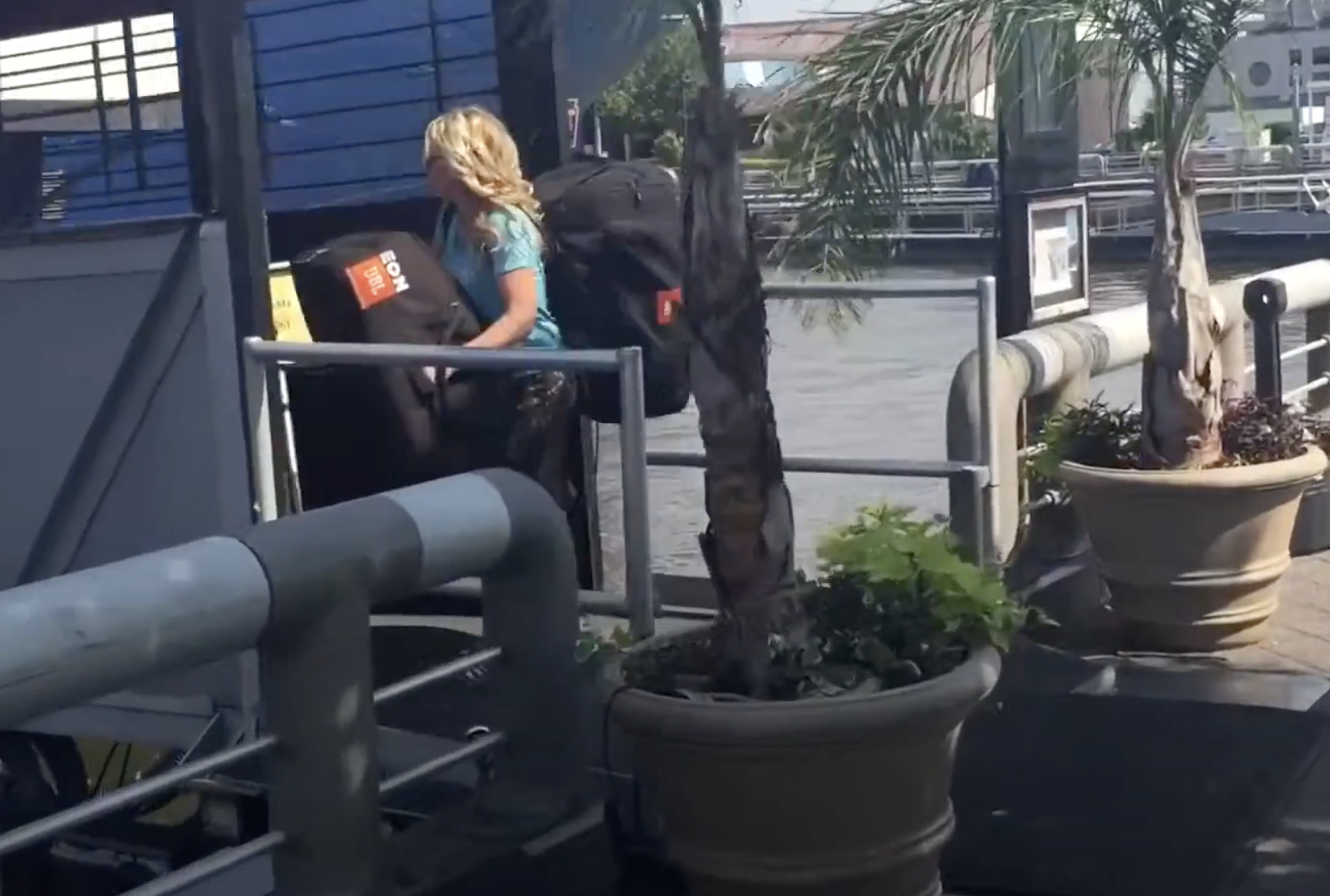 Female DJ DeeJay Shelly carrying two JBL speakers at the Moshulu waterfront in Philadelphia.