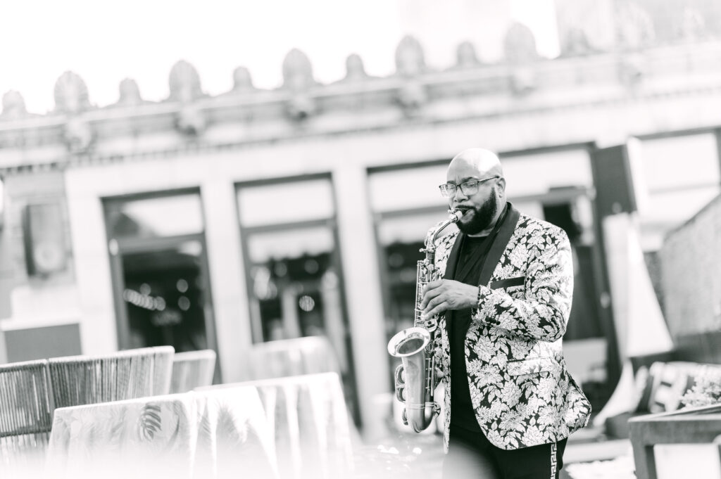Black-and-white photo of John “Sax” Williams playing saxophone during a DJ and Sax performance at the Stratus Rooftop Lounge in Philadelphia, Pennsylvania.